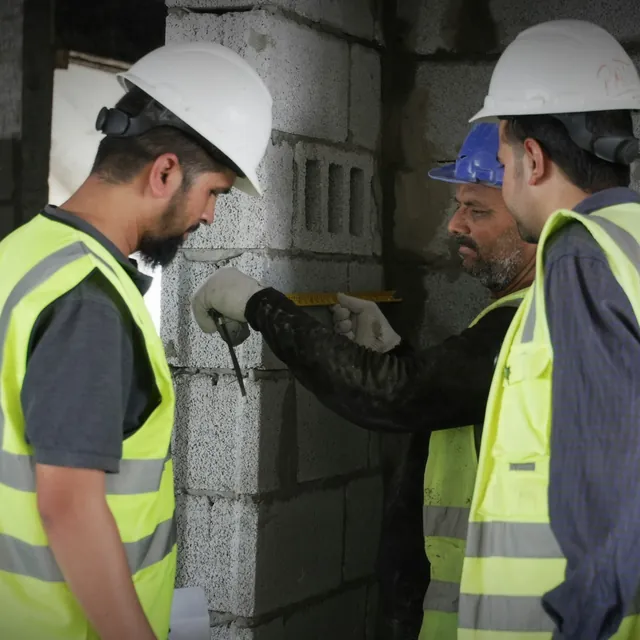 Equipo de obra midiendo un muro